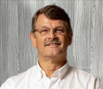 male employee posing with glasses and a white SERVPRO collared-shirt