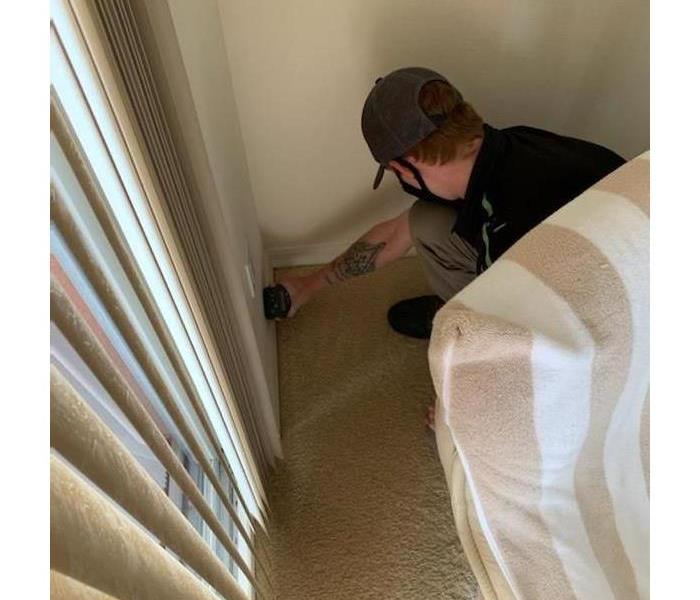 SERVPRO technician by wall using a moisture detection device