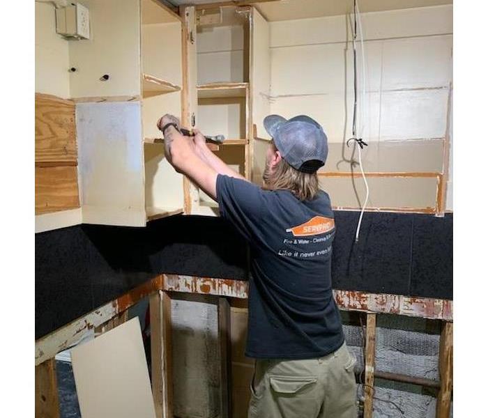 SERVPRO employee removing cabinets in a kitchen