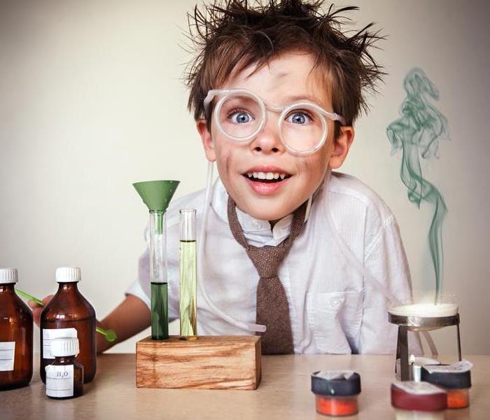 A child with a burning science experiment with smoke on his face. 