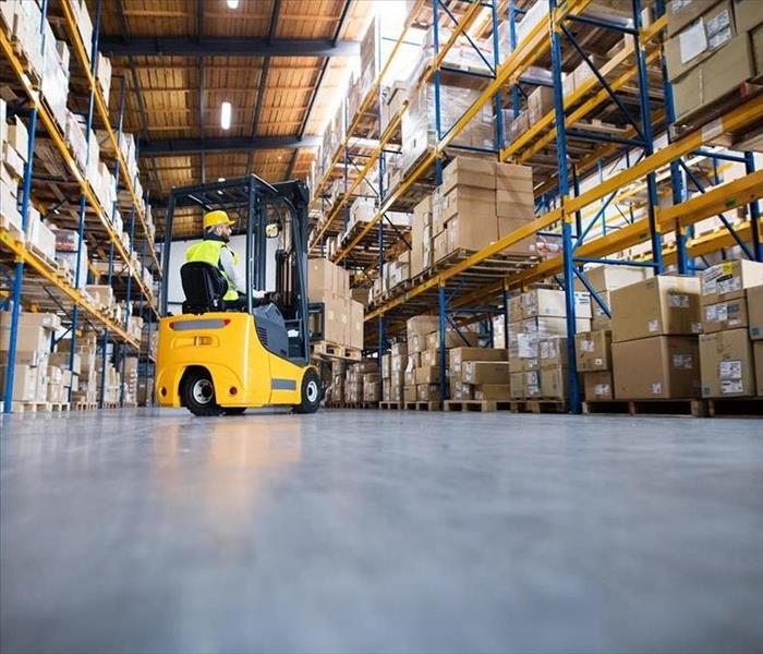 Man driving forklift in warehouse.