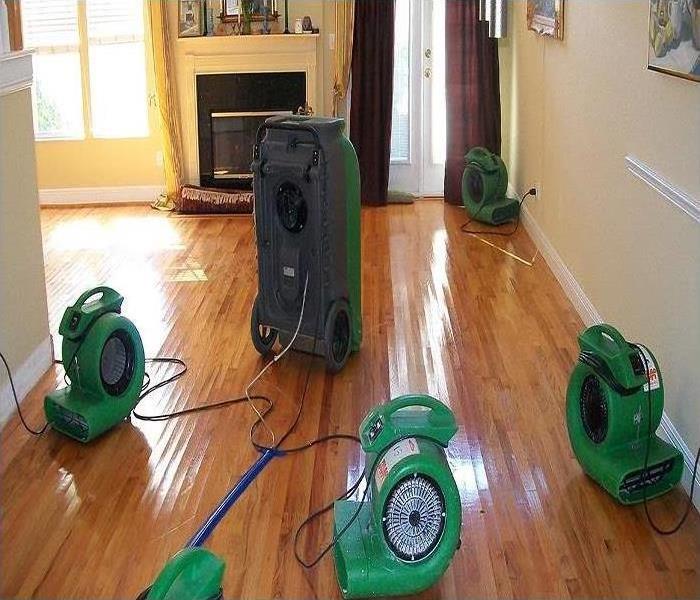  air movers, refrigerant dehumidifiers, and desiccant dehumidifiers set up in this home drying the hard wood floors